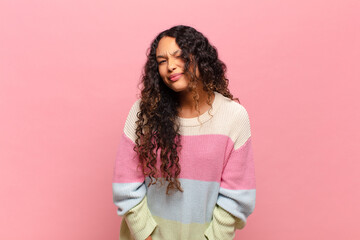 young hispanic woman looking happy and friendly, smiling and winking an eye at you with a positive...
