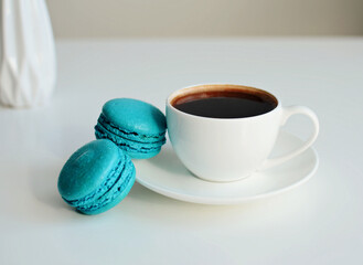 White cup of coffee, multicolored macaroons on white background, close up