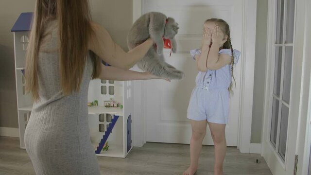 Mom gives a kitten to her daughter. Happy little girl jumping and laughing. Little girl receives a kitten as a gift . Beautiful little girl wint long blond hair.