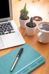 Wooden working desk with laptop computer, smartphone, office supplies and coffee