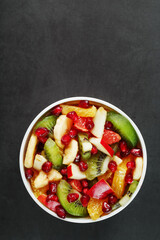 Fototapeta na wymiar Fresh fruit salad cup made of juicy fruits on a black background.