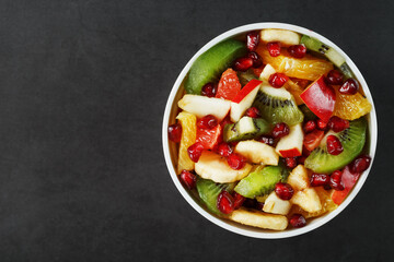 Fresh fruit salad cup made of juicy fruits on a black background.