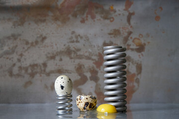 Quail eggs and metal springs. Egg yolk on a steel surface. Copy space. 