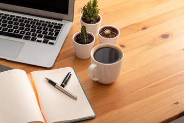 Wooden working desk with laptop computer, smartphone, office supplies and coffee