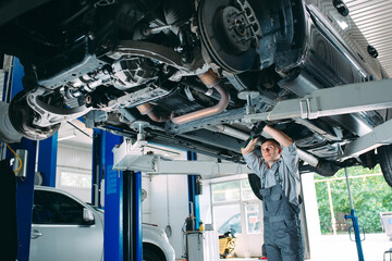 Portrait of a mechanic repairing a lifted car.