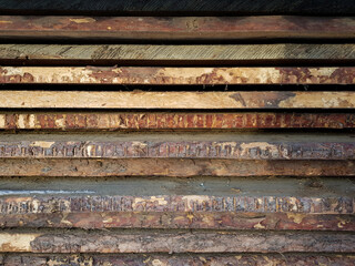 natural wooden boards stacked in a row on top of each other in a horizontal position as a background. decorative solution, shabby brown wooden planks with shabby bark. in the daytime, without people. 