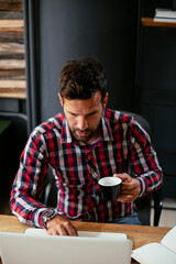 Young businessman drinking coffee in his office. Businessman on coffee break.