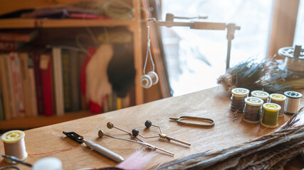Fishing fly tying materials and tools on a wooden table - obrazy, fototapety, plakaty