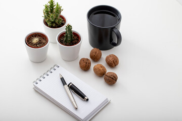 Top view work desk. With coffee, snack walnuts, tiny cactus and notepad