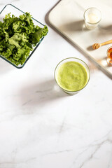 Healthy green kale smoothie with greek yogurt, almond n honey in glass isolated on white table background,top view. Kale is considered a superfood because it's a great source of vitamins and minerals.