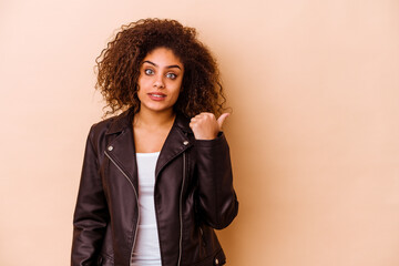 Young african american woman isolated on beige background shocked pointing with index fingers to a copy space.