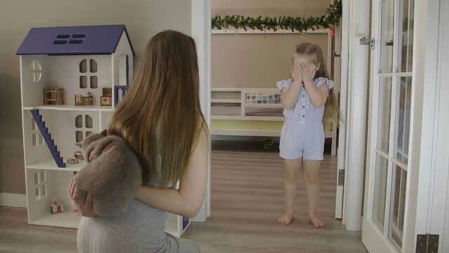 Mom gives a kitten to her daughter. Happy little girl jumping and laughing. Little girl receives a kitten as a gift . Beautiful little girl wint long blond hair.