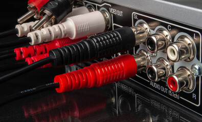 modern multimedia and audio equipment with attached cables on black background close -up