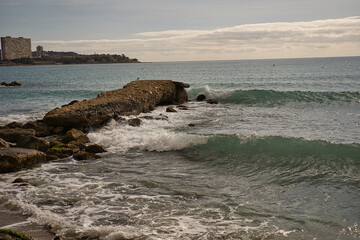 Sea waves lash line impact rock on the beach, located in Alicante