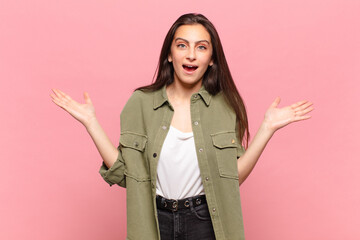young pretty woman looking shocked and astonished, with jaw dropped in surprise when realizing...