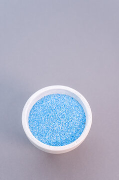 Vertical Shot Of Blue Food Glitter In White Cup Isolated On Purple Background