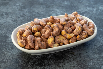 Shelled cashew on plate on dark background