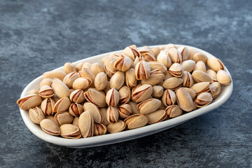 Pistachios on plate on dark background
