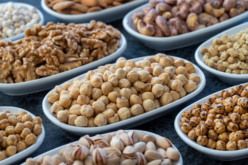 Hazelnuts in selective focus. Nuts on plate on a dark background. Walnut, Chickpeas, White Chickpeas, Dry mulberry, almond, cashew, pistachio. Types of nuts on the plate.