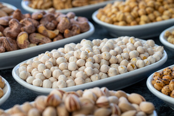 White Chickpeas in selective focus. Nuts on plate on a dark background. Walnut, Chickpeas, White Chickpeas, Dry mulberry, almond, cashew, pistachio. Types of nuts on the plate.