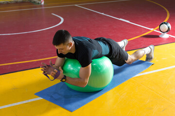 Athletic guy in sportswear and fitness tracker doing exercises in gym.