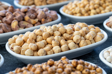 Hazelnuts in selective focus. Nuts on plate on a dark background. Walnut, Chickpeas, White Chickpeas, Dry mulberry, almond, cashew, pistachio. Types of nuts on the plate.