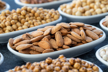 Almond in selective focus. Nuts on plate on a dark background. Walnut, Chickpeas, White Chickpeas, Dry mulberry, almond, cashew, pistachio. Types of nuts on the plate.