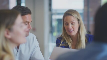 Close up of business team sitting around table in office having informal discussion together - shot in slow motion