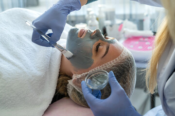 beautician applying facial mask for female client at spa salon