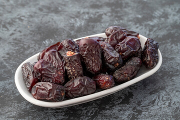 Date fruit on plate on dark background