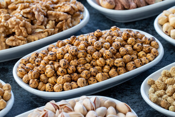 Roasted chickpeas in selective focus. Nuts on plate on a dark background. Walnut, Chickpeas, White Chickpeas, Dry mulberry, almond, cashew, pistachio. Types of nuts on the plate.
