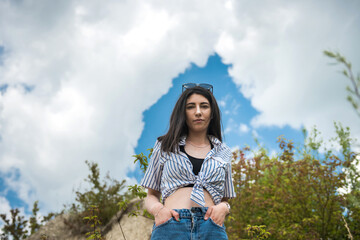 Slim sexy young woman posing near big stone and green tall grass