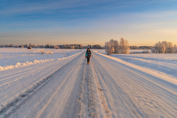 Fototapeta na wymiar A beautiful woman wearing colourful cloth walking on the empty road with snow covered landscape