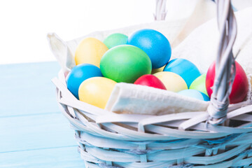 basket with colorful Easter eggs on a blue wooden background, selective focus, tinted image