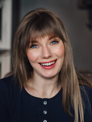 Close up Image of young adorable smiling blonde pretty woman with blue eyes enjoying life in trendy city cafe vertical portrait for social platform stories