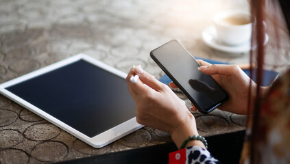 Focus on smart phone in hand, young female using smart phone and digital tablet working