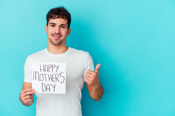 Young caucasian man holding a happy mothers day placard isolated smiling and raising thumb up