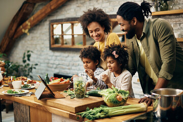 Happy African American family preparing healthy food in the kitchen. - Powered by Adobe