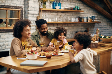 Happy African American family relaxing while talking at dining table.