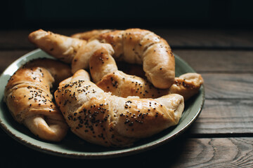 Freshly baked homemade croissants on wooden table. Selective focus. Fresh out of the oven. Breakfast or brunch concept.