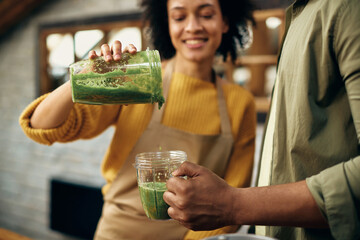 Close-up of African American couple drinking green smoothie at home.