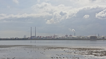 Fototapeta na wymiar Misty view from across the water on Poolberg peninsula, with the chimneys of the power generation station in Dublin, Ireland