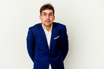 Fototapeta premium Young business caucasian man isolated on white background shrugs shoulders and open eyes confused.