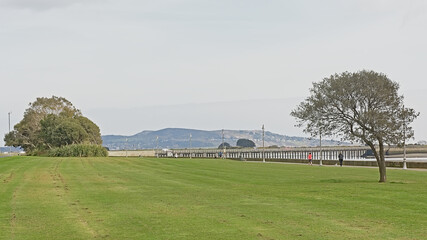 Obraz premium City park in dublin with Howth peninsula in the fog in the background