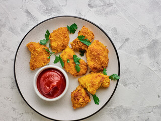 Homemade chicken nuggets and ketchup in a plate top view.
