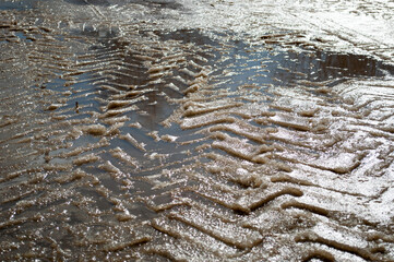Tracks from a tractor tread on melted snow. Footprints in the melted snow.