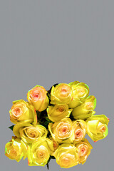Bouquet of yellow tender roses on a gray background, vertical frame, copy space. Greeting card for mother's day, birthday, wedding day