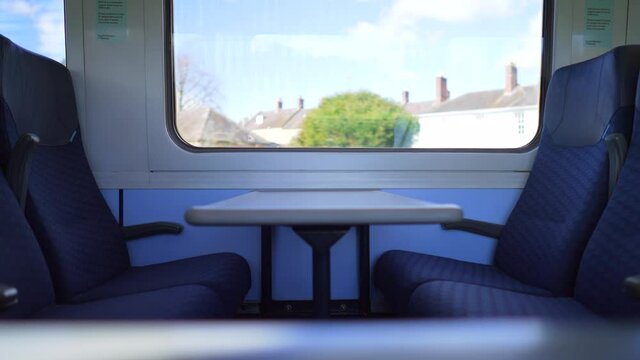 Empty seats and table in a moving train in the countryside during Covid-19 Coronavirus pandemic, no commuting, no travelling and cancelled holidays, on a sunny day