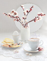 Still life with cappuccino coffee and a branch of blossoming apricot on a white background