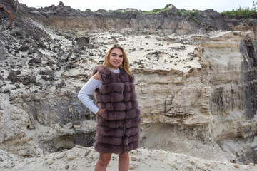 Fototapeta na wymiar pretty girl in casual cloth and fur coat sand rocks